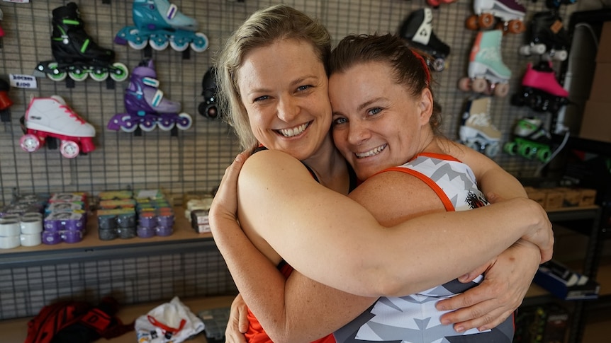 Two women hug in a rollerblade store.