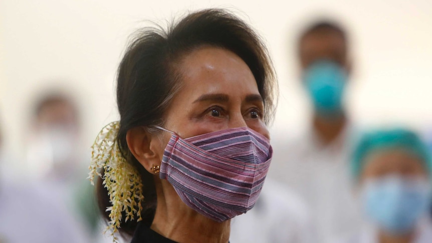 A person with brown hair and wearing a colourful face mask stairs off camera.