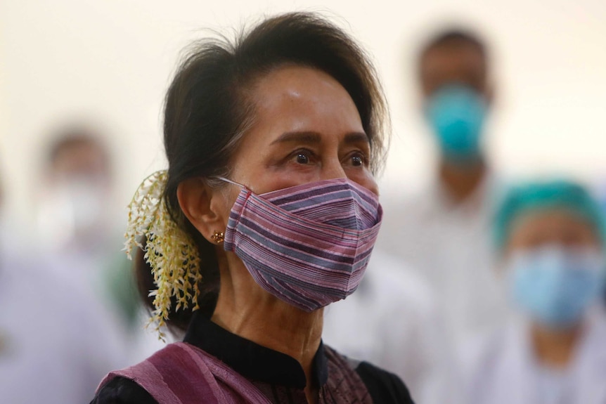 A person with brown hair and wearing a colourful face mask stairs off camera.