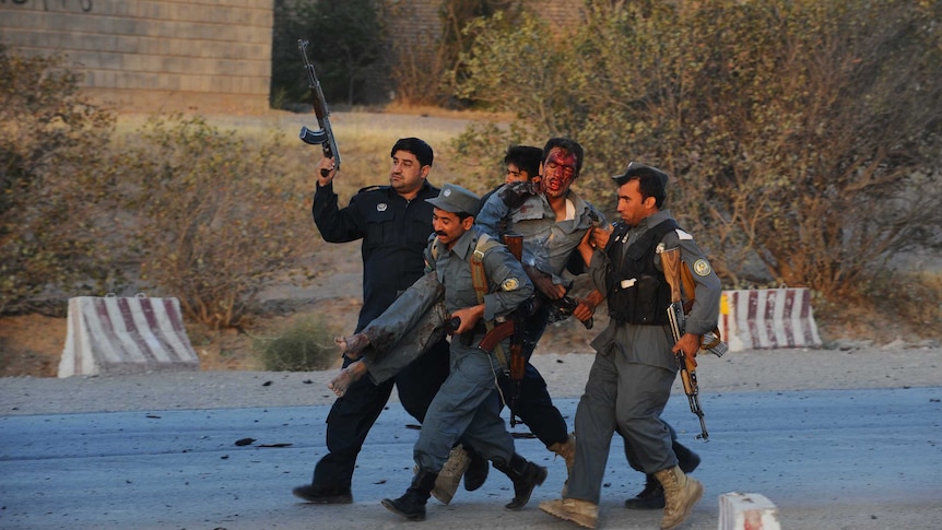 Wounded policeman covered in blood is helped to safety.