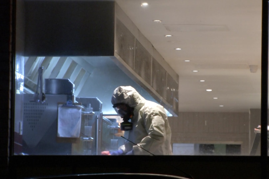 A person in full PPE inside a restaurant doing a deep clean.