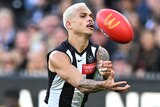 Bobby Hill handballs with his left hand during a Collingwood AFL match at the MCG.