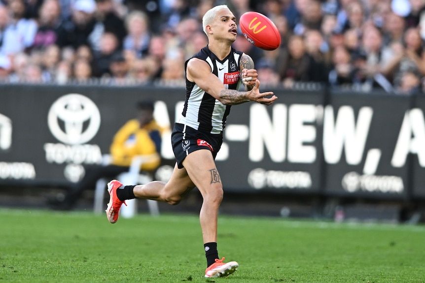 Bobby Hill handballs with his left hand during a Collingwood AFL match at the MCG.