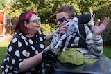 Margie Anderson crouches to talk to her son Elias, who is in a wheelchair