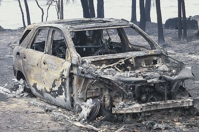 A burnt-out car with melted wheels, bonnet and glass.