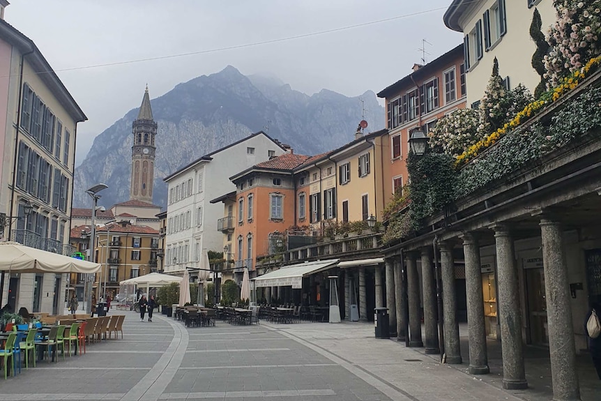Picture of empty street in Lecco, Italy with mountain in background.