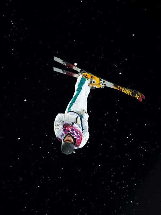 A skier upside down with a starry night sky behind him.