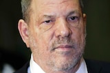 Harvey Weinstein wears a black suit, white shirt and blue tie and looks to the right.