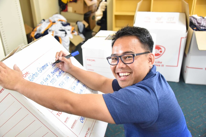 Father Junray Ryanga, originally from the Philippines writing Girton Grammar on a box.