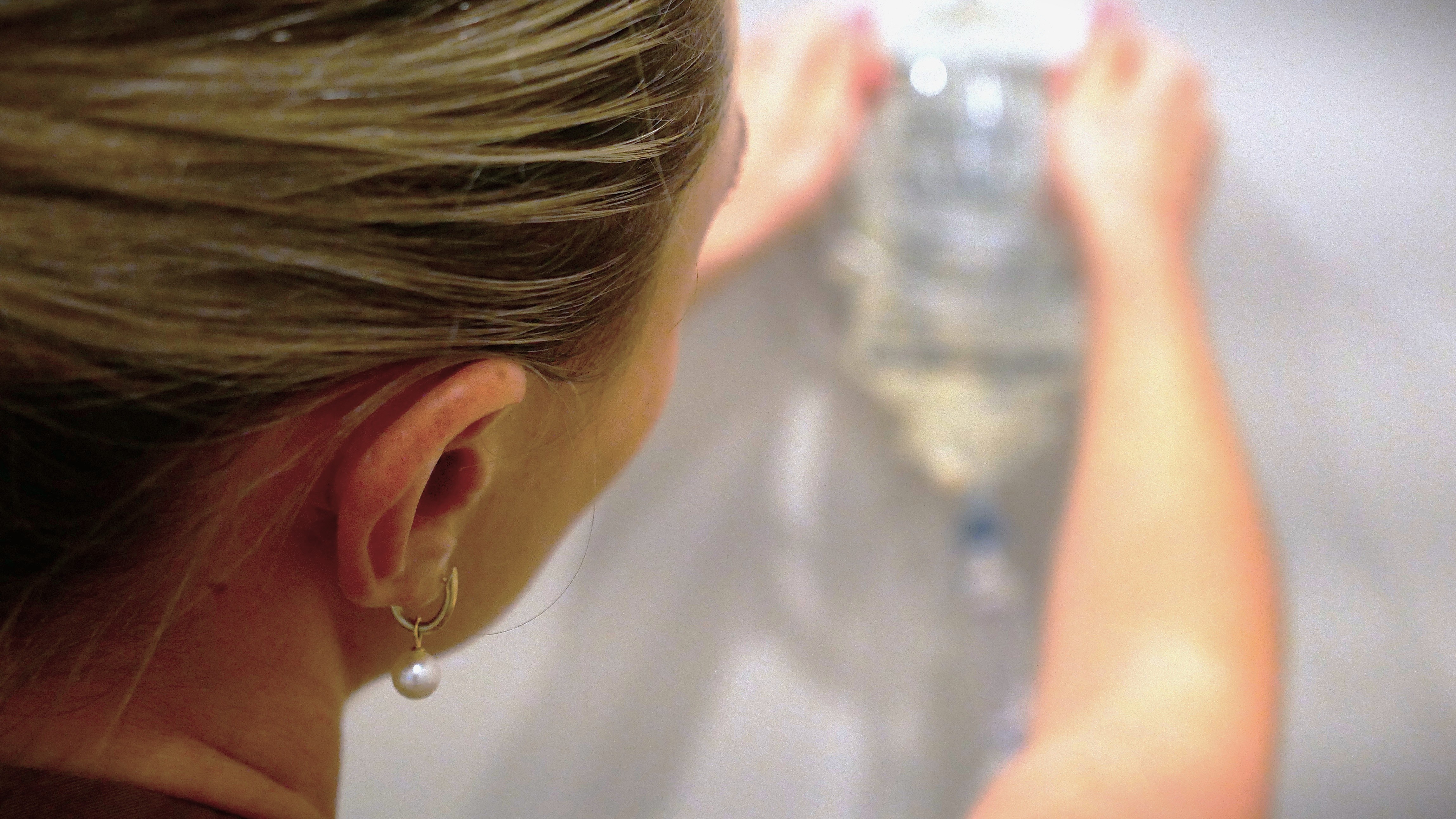 An IV drip bag hangs on the wall behind a woman's head.