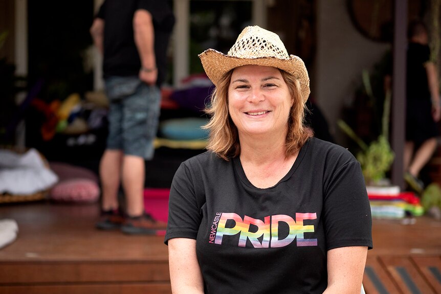 A woman in a straw hat and black Newcastle Pride T-shirt