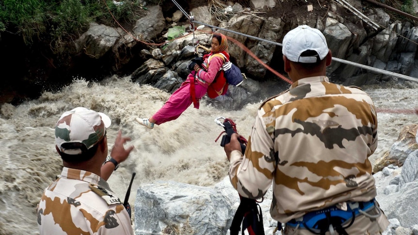 An Indian woman is transported across a flooded river.