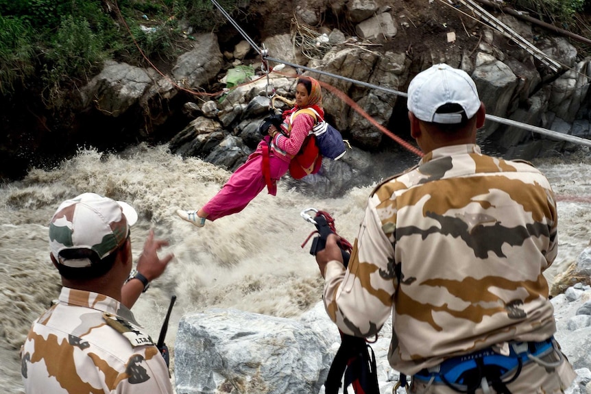 An Indian woman is transported across a flooded river.