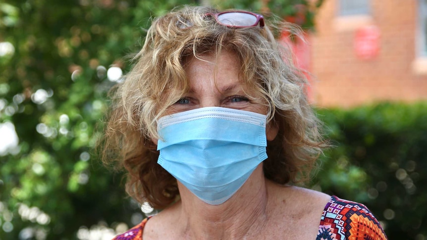 A woman with curly hair in a mask on a street