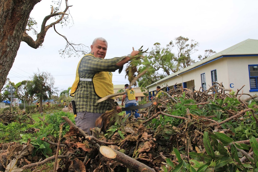 Medium shot of a man cleaning up tree branches.