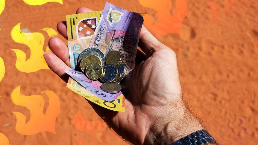 Hand holding Australian money with red dirt below and illustrated flames for a story about helping with bushfire appeals.