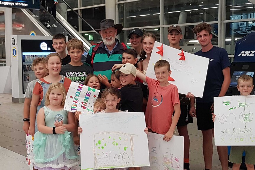 A grandfather surrounded by his grandchildren at Sydney Airport.