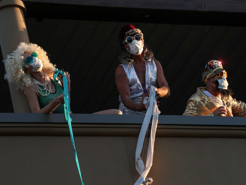 Lisa, Andrew and Carl wear wigs, glasses and safety masks and pretend to escape off their balcony