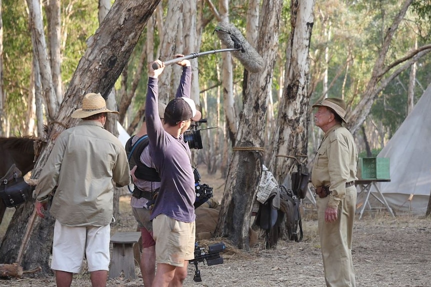 A film crew captures a scene involving Jack Thompson while filming in the bush