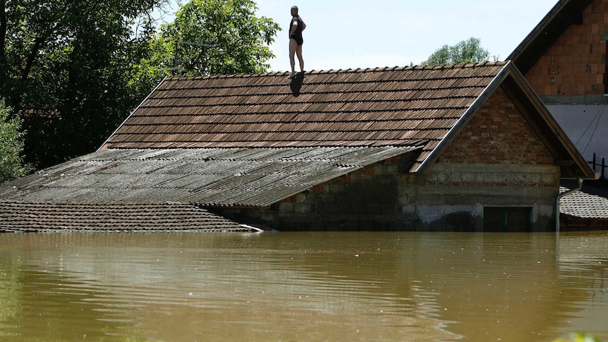 A man waits to be rescued from the roof of his house during heavy floods in Vojskova, Bosnia.