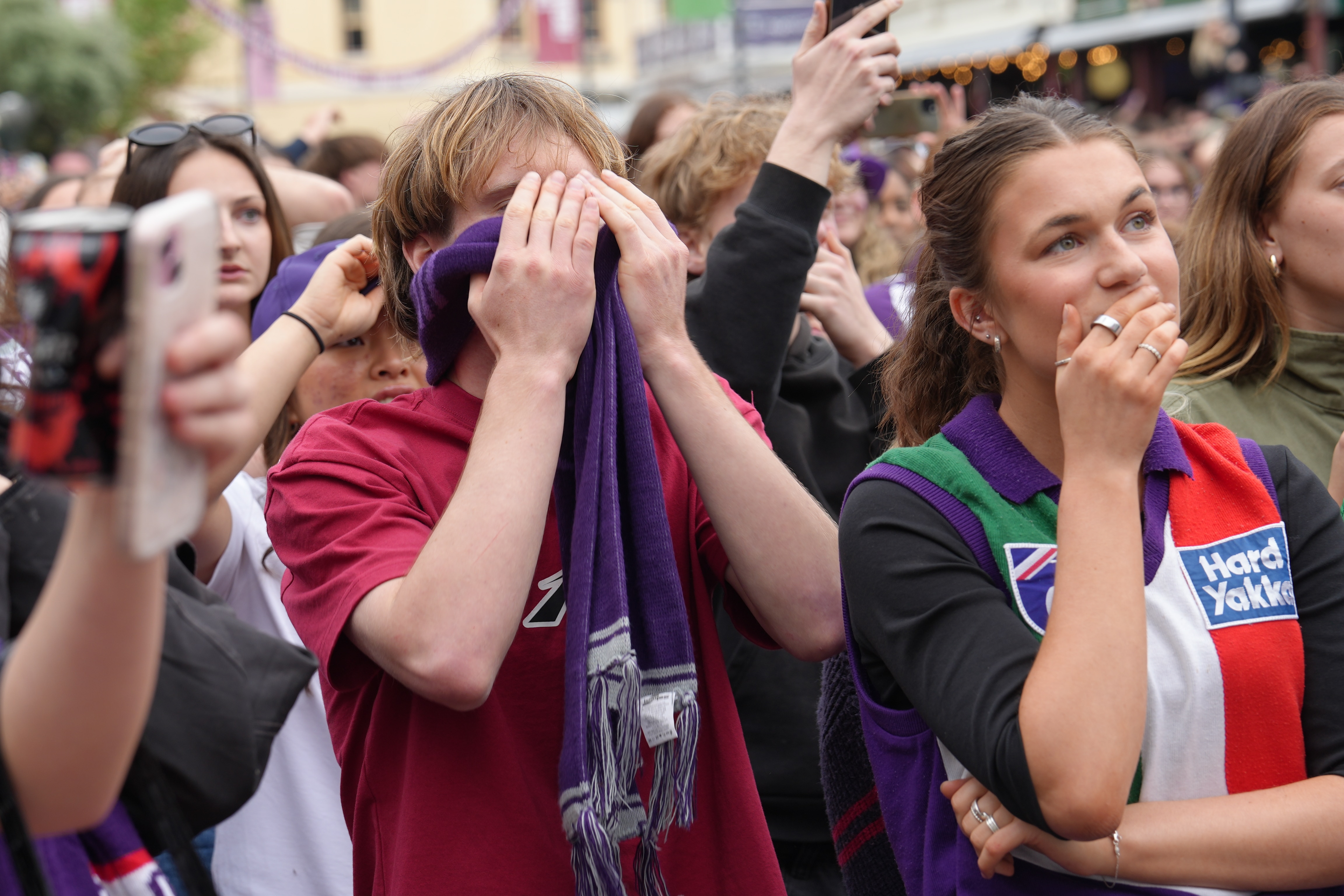 Fremantle fans wearing club merchandise hold their heads in their hands 