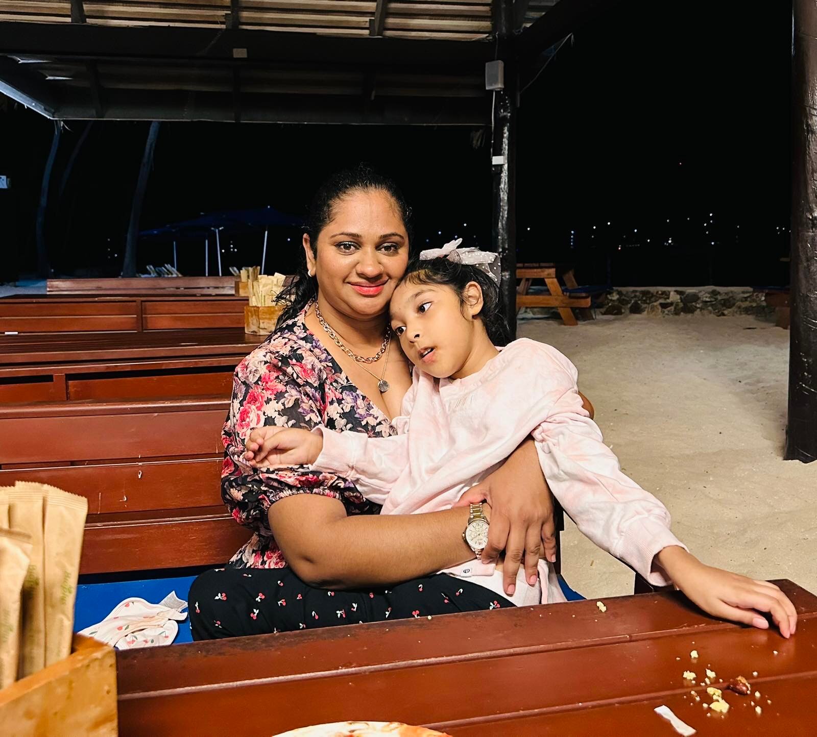 A mother sits hugging her nine-year-old daughter was born with cerebral palsy, a permanent motor disability.