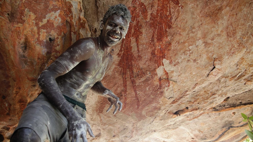 Indigenous boy from Balanggarra country in front of rock paintings