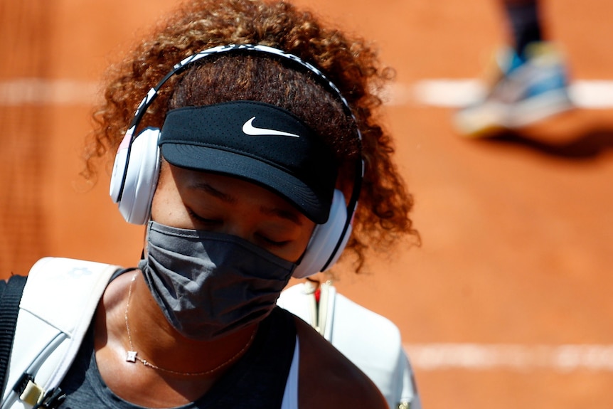 Naomi Osaka wears a face mask and headphones.