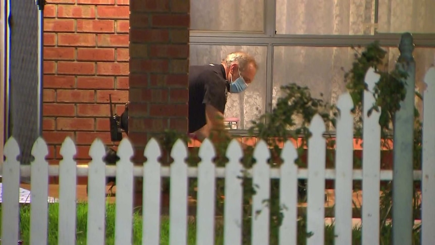 A police officer looks for evidence outside a home.