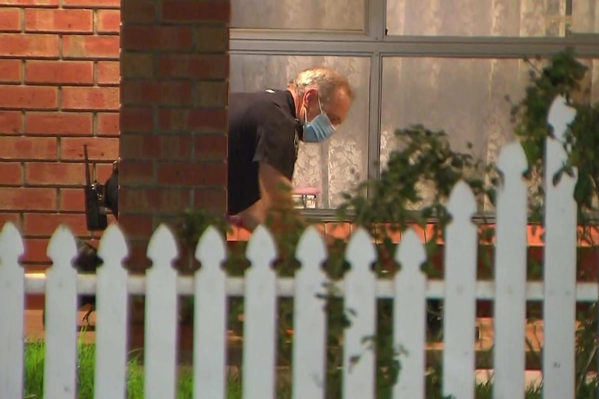 A police officer looks for evidence outside a home.