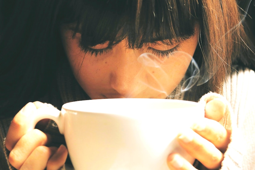 Close up of a woman drinking a large cup of coffee