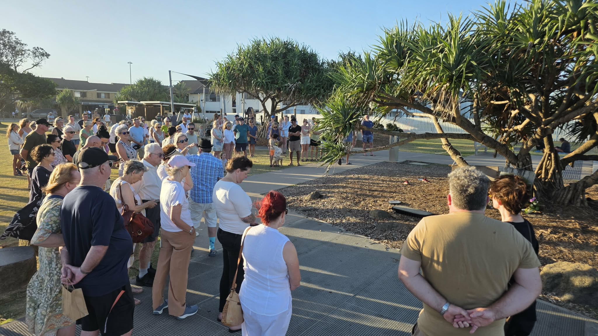 Um grupo de pessoas está de pé com a cabeça baixa.