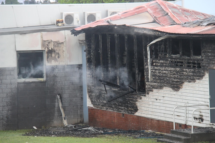 A school building with blackened walls and smoke coming out