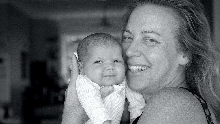 A black and white shot of a mum holding a baby.