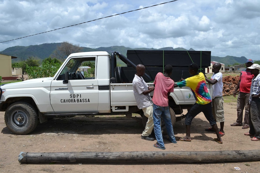 Mozambican men load coffins of victims of alcohol poisoning onto a pickup truck
