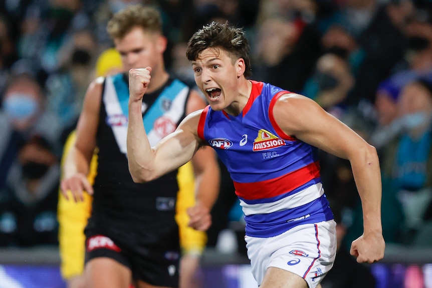 A Western Bulldogs AFL player pumps his right fist as he celebrates kicking a goal against Port Adelaide.