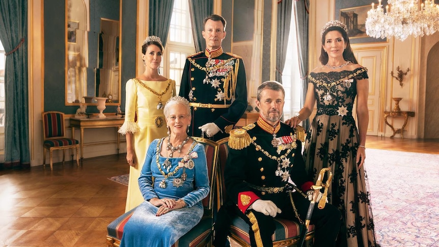 Five people in royal attire pose for a portrait, Queen Margrethe and Prince Frederik are seated at front adorned in jewels
