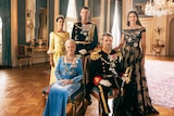 Five people in royal attire pose for a portrait, Queen Margrethe and Prince Frederik are seated at front adorned in jewels