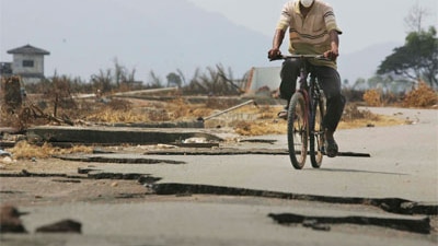 A man rides a bike through Banda Aceh after the 2005 tsunami