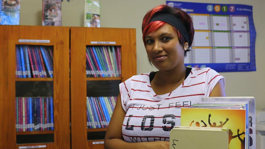 An African woman with red and black hair sitting at a library desk.