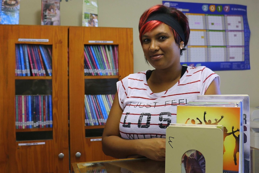 An African woman with red and black hair sitting at a library desk.