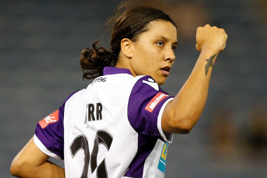 Sam Kerr in a Perth Glory uniform holds her fist in the air in celebration