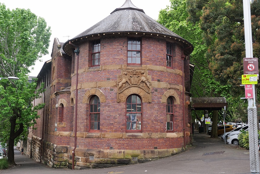 An old red brick building with a sandstone insignia