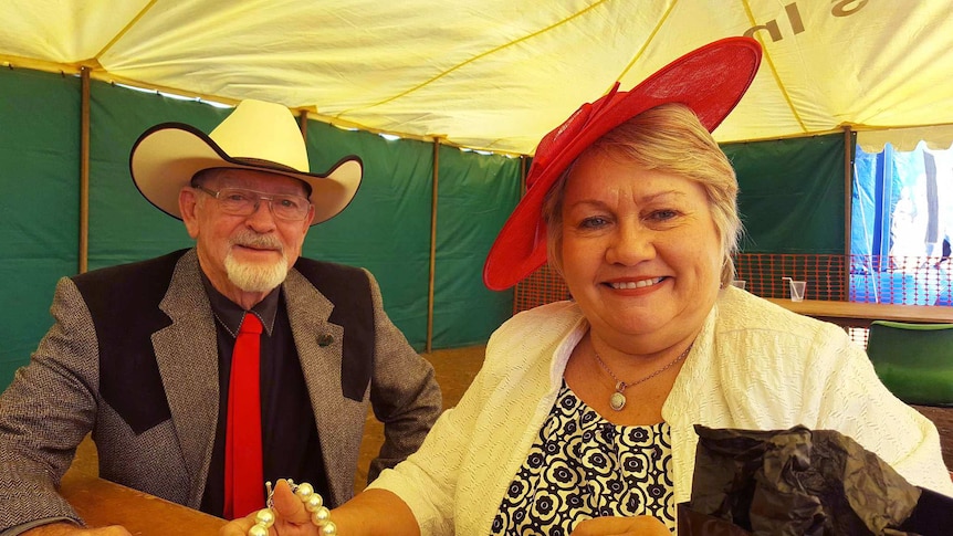 A well dressed couple in racewear sitting in a marquee.