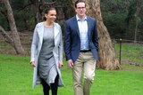 Anne Aly and Matt Keogh walk side by side on grass at a photo call.