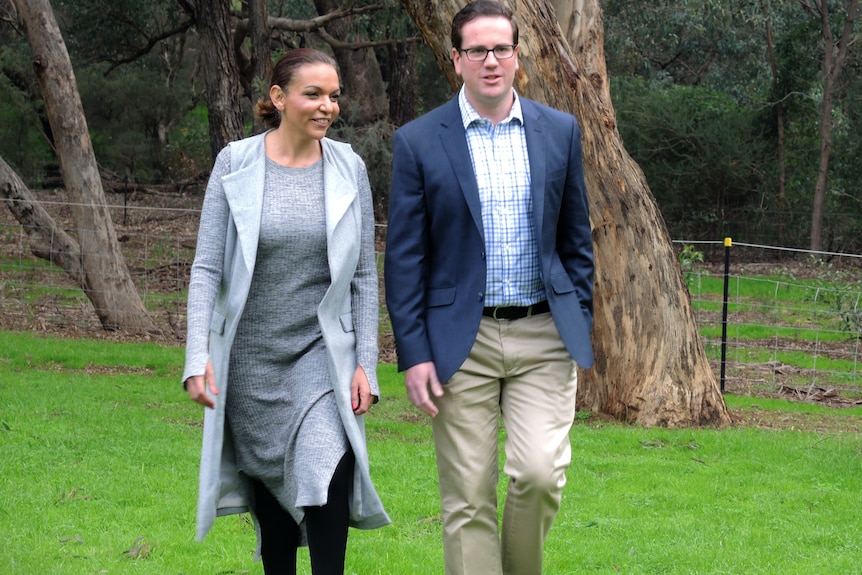 Anne Aly and Matt Keogh walk side by side on grass at a photo call.