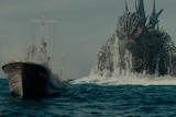 Godzilla stalks a boat from behind while they are both in the sea