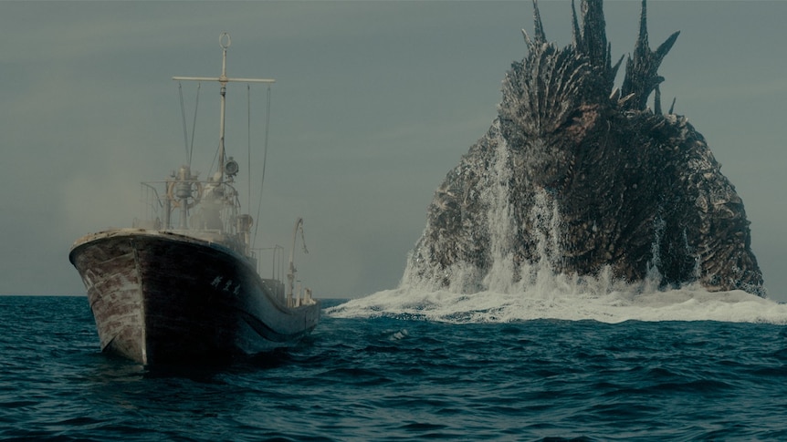 Godzilla stalks a boat from behind while they are both in the sea