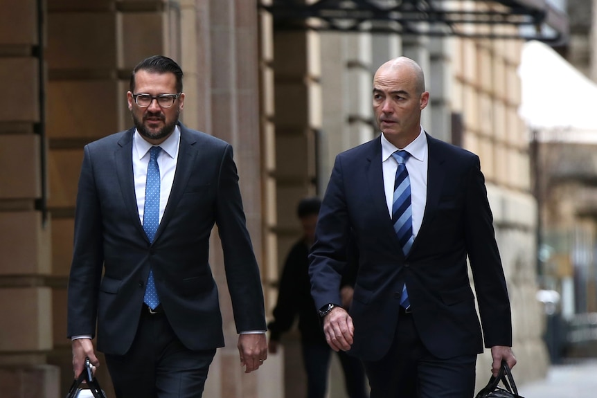 Two suited men walking down a city street.