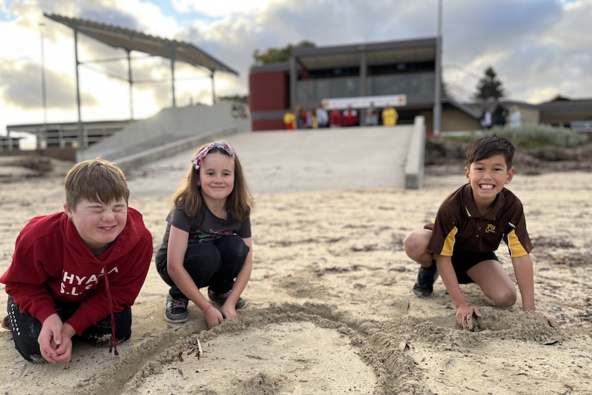 Jacob Barlow, 11, Isabella Barlow, 9, and Sammy Ramsay, 9, playing in the sand in front the Whyalla Surf Life Saving Club. Ausnew Home Care, NDIS registered provider, My Aged Care